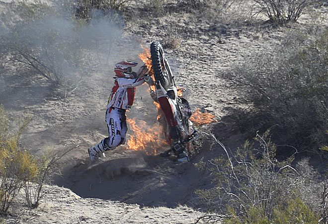 Paulo Gon�alves trata de apagar el fuego de su moto.